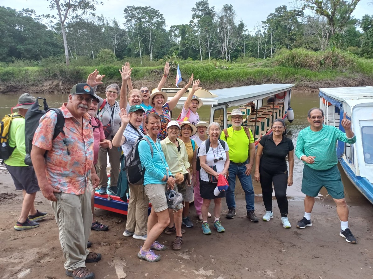 Grupo de pasajeros contentos junto a los botes